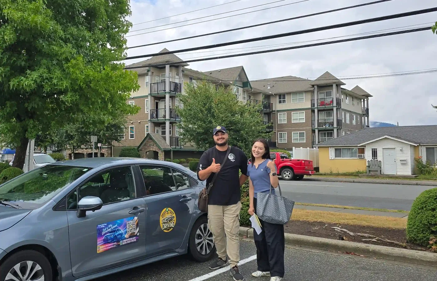 New driver standing with her instructor beside the Right of Way training car